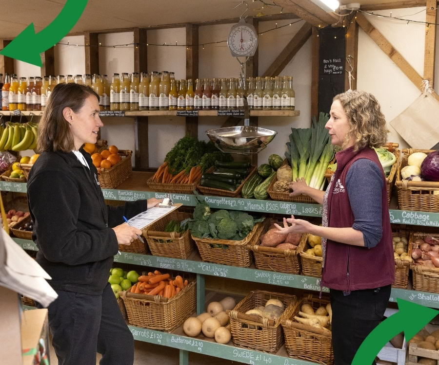 Two people chatting in a farm shop with a clipboard